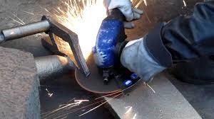 Man grinding away a material using an electric grinder and PPE